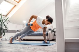 Woman doing at-home workouts using weights in living room