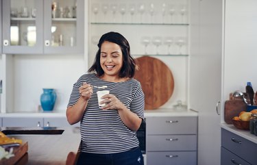 A young adult in the kitchen eating yogurt as a natural remedy for diarrhea