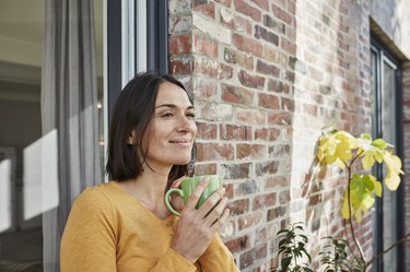 Smiling woman standing outside and drinking tea as a natural remedy for heachaches