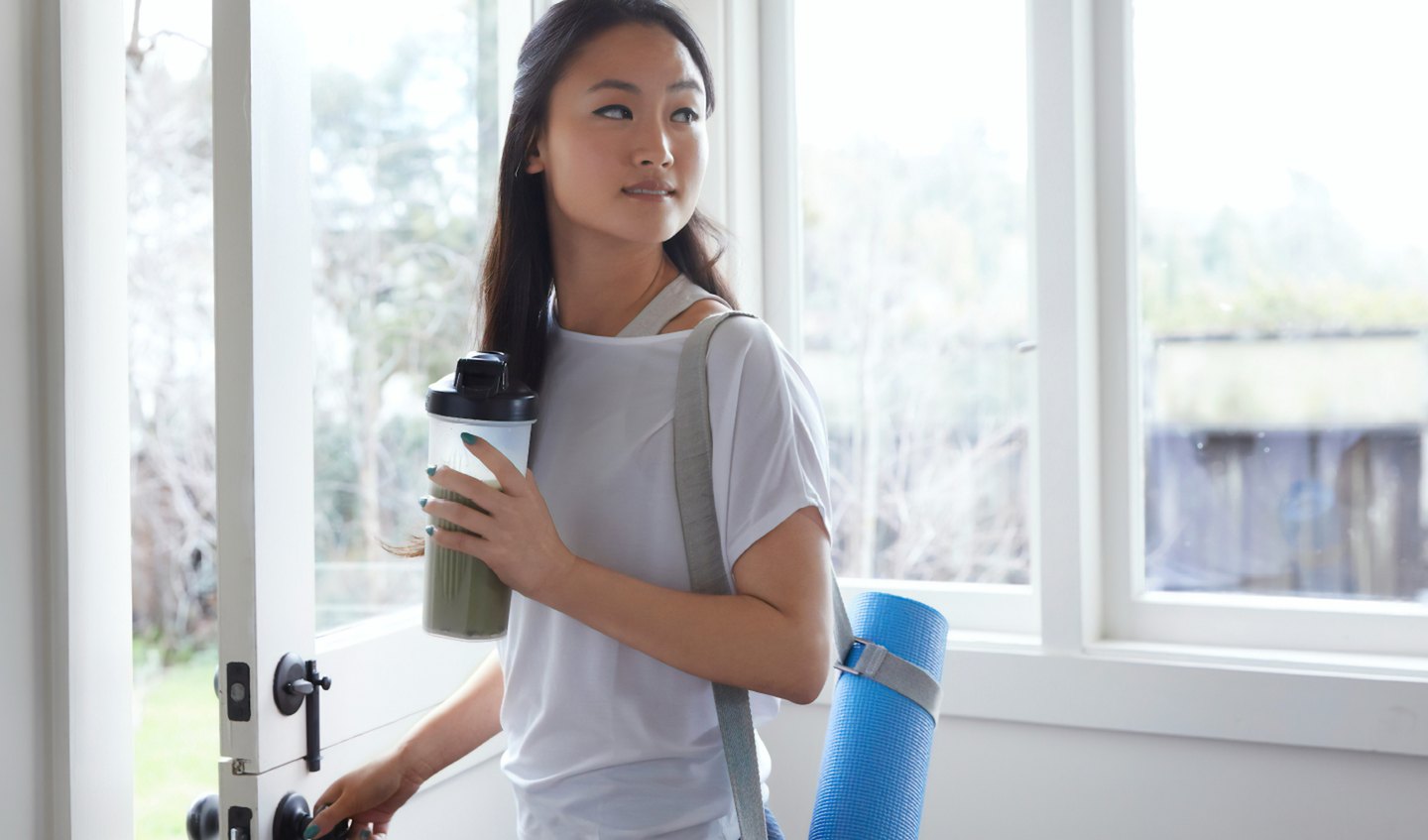 A woman leaving a yoga studio with a nutrition shake in her hand