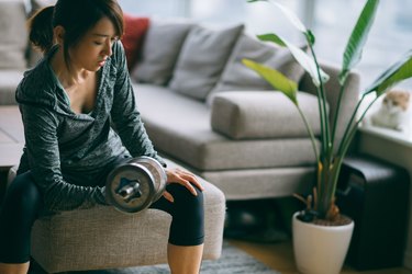 Japanese woman in fitness attire performing arm curls with dumbbell