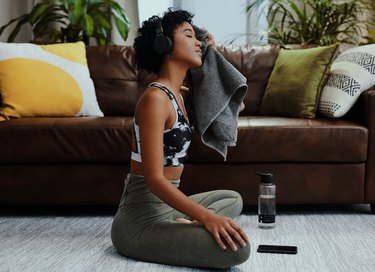 Woman wiping sweat on face after towel workout.