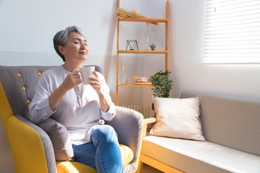 adult at home smiling and drinking a cup of tea, as a natural remedy for upset stomach