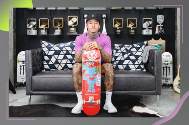 skateboard Nyjah Huston holding skateboard sitting on gray couch