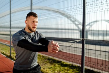 young fit man doing a resistance band pallof press outside