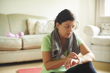 A person in their 40s checking their fitness tracker and exercising to lose weight